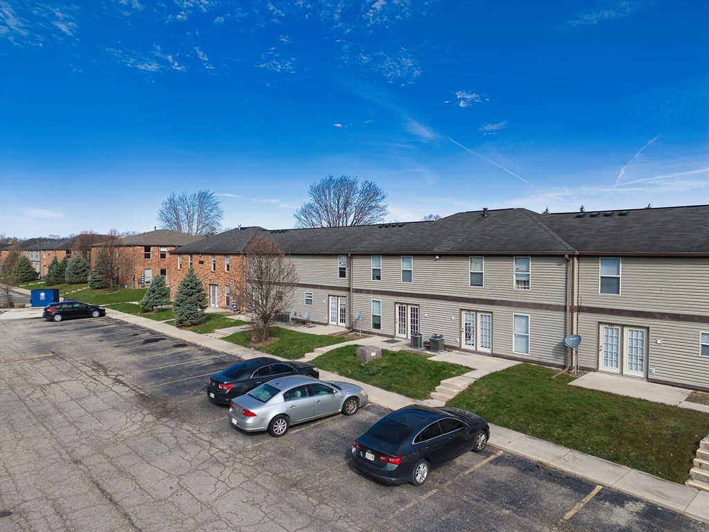 an aerial view of an apartment complex with cars parked in a parking lot