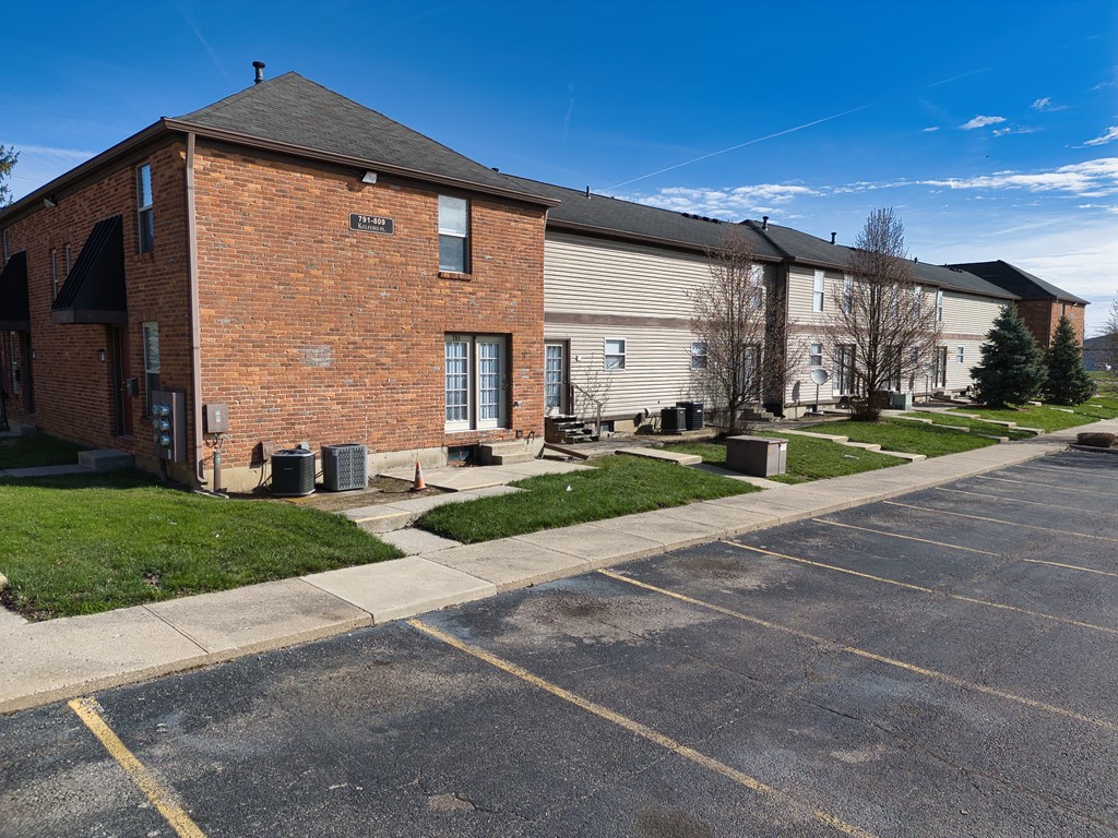 a brick building with a sidewalk and a parking lot
