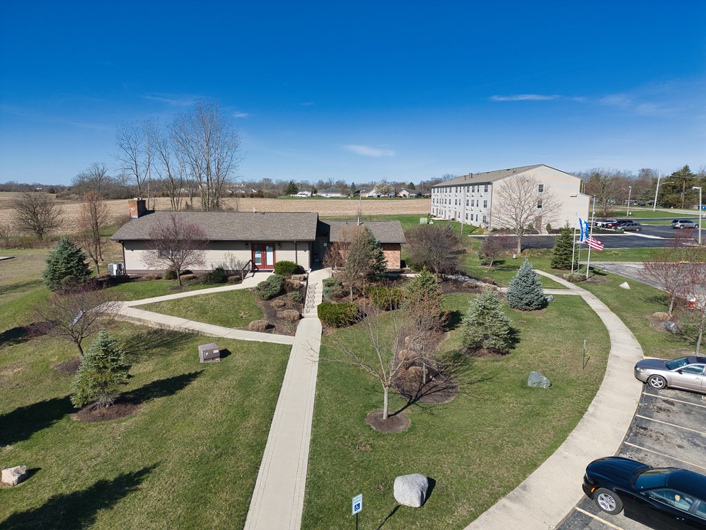 an aerial view of a park with trees and a sidewalk and a building