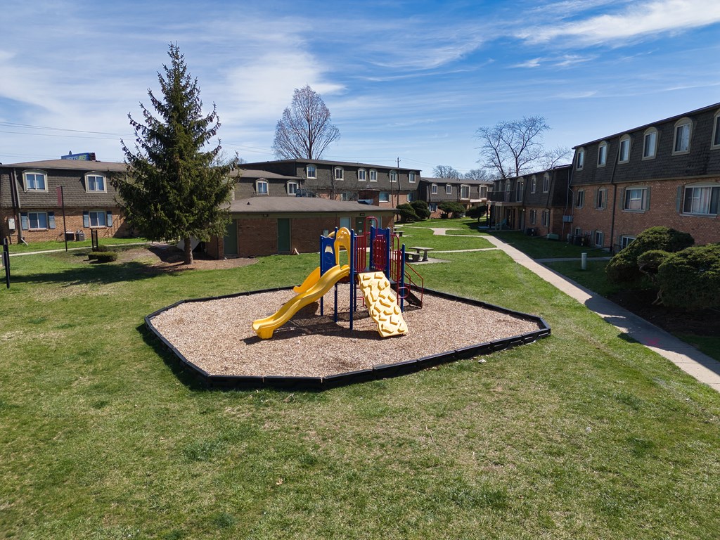 a playground in a yard in front of an apartment building