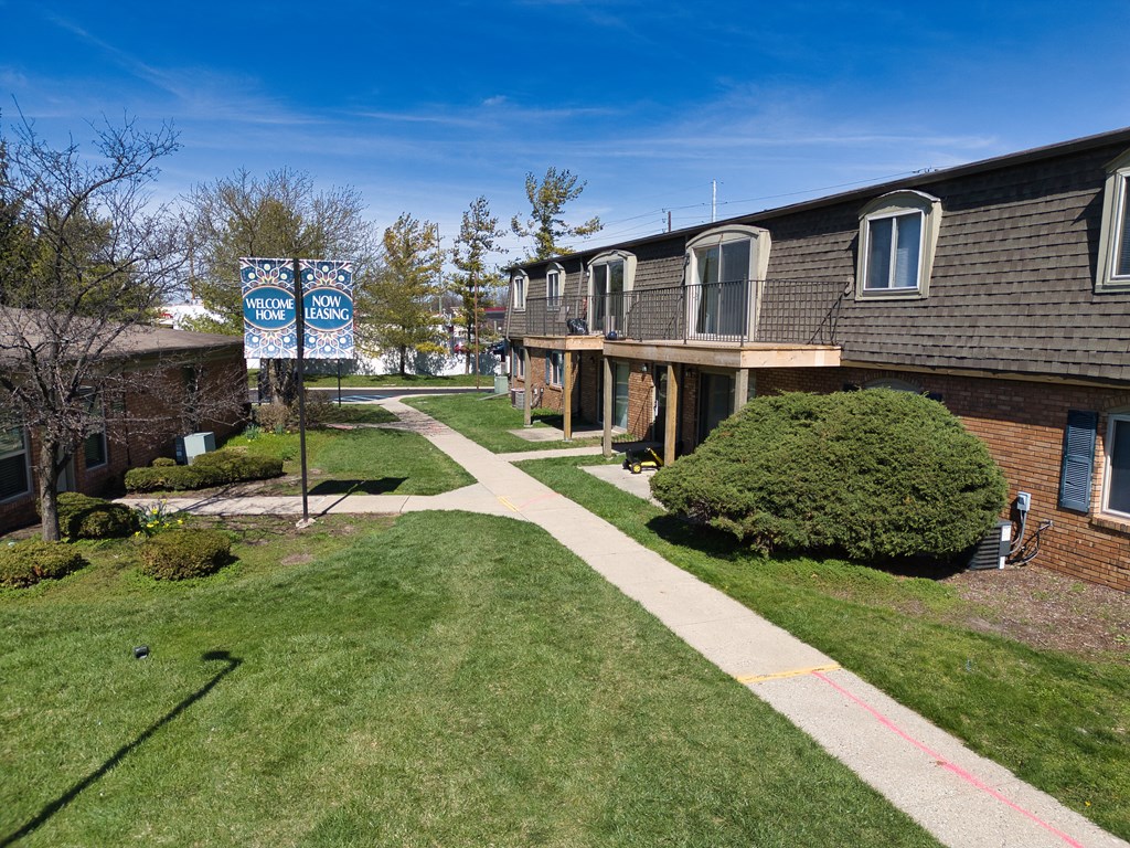 an apartment building with a sidewalk and a blue street sign