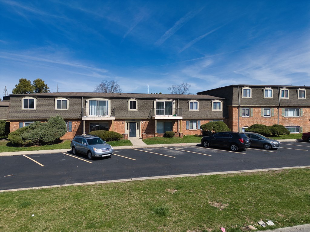 an apartment building with cars parked in the parking lot