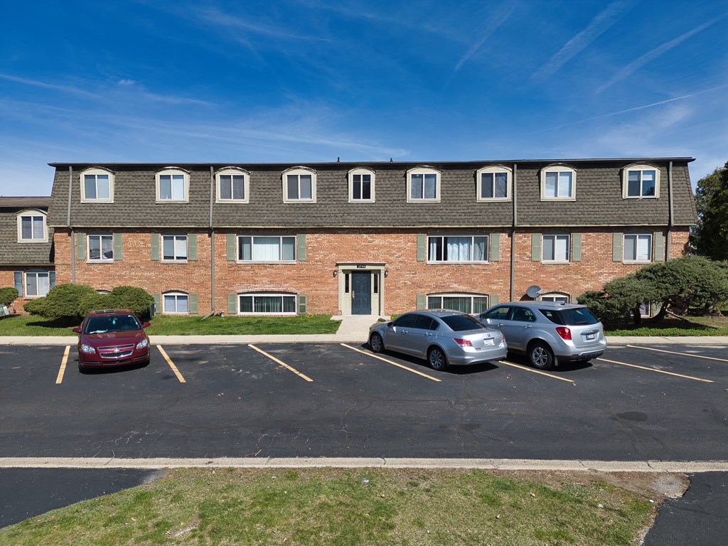 a large brick apartment building with cars parked in a parking lot