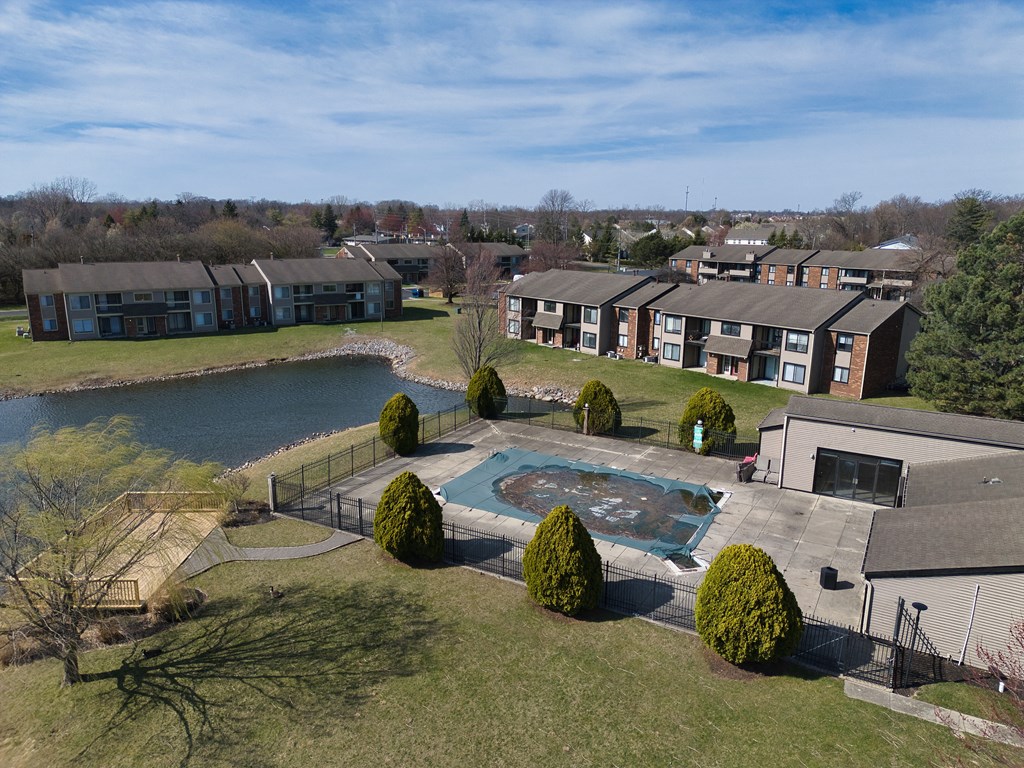an aerial view of an apartment complex with a swimming pool and a lake