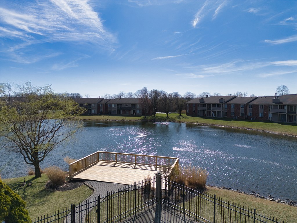 the view of a pond with a bridge in front of an apartment building