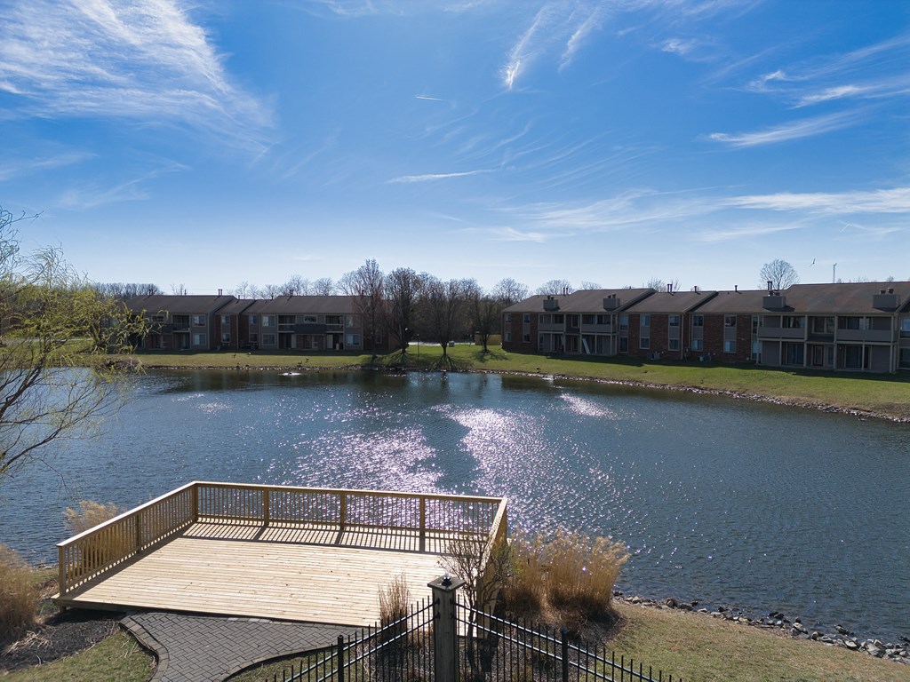 a large pond with a wooden dock in front of some apartments