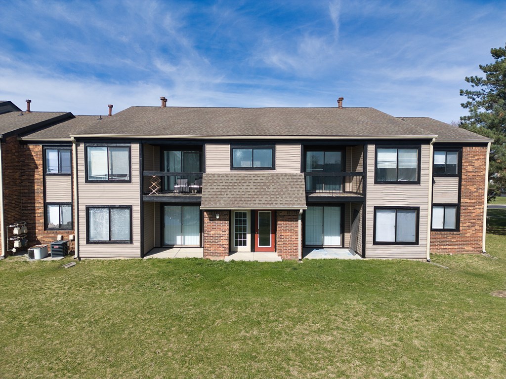 a large apartment building with a lawn and a blue sky