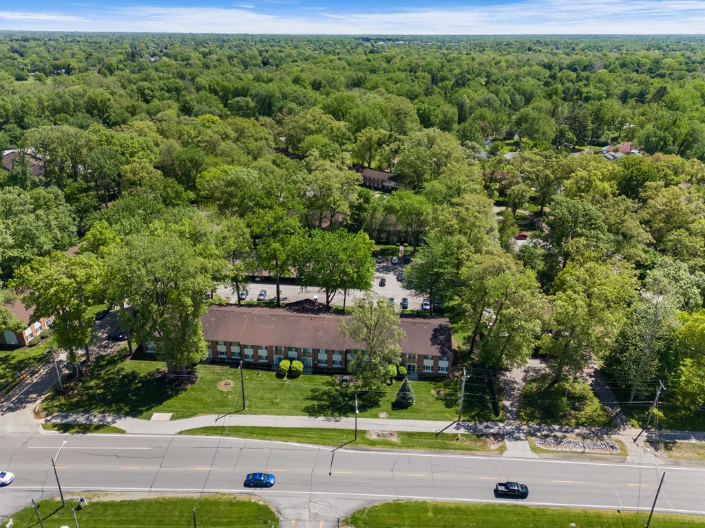 an aerial view of a building surrounded by trees and a street