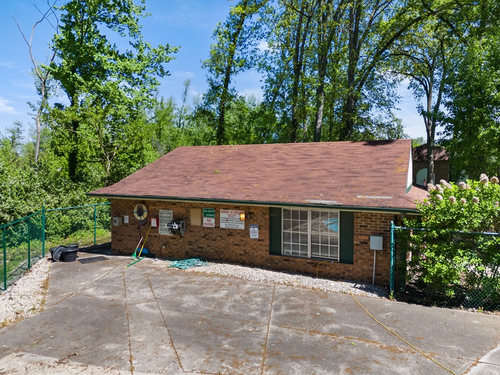 a small brick house with a driveway and trees