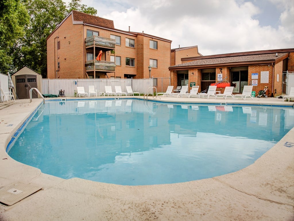A large swimming pool in front of a building with a red brick exterior.