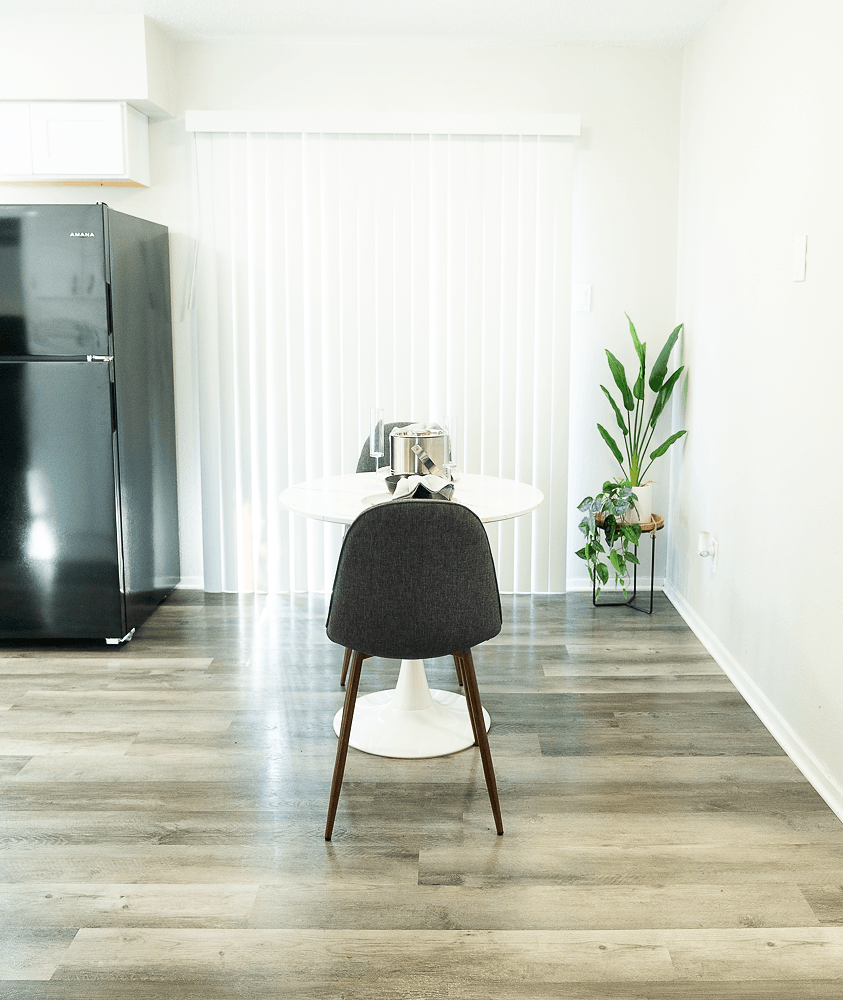 a living room with a black refrigerator and a white table at La Bella Apartments, Fort Worth, Texas