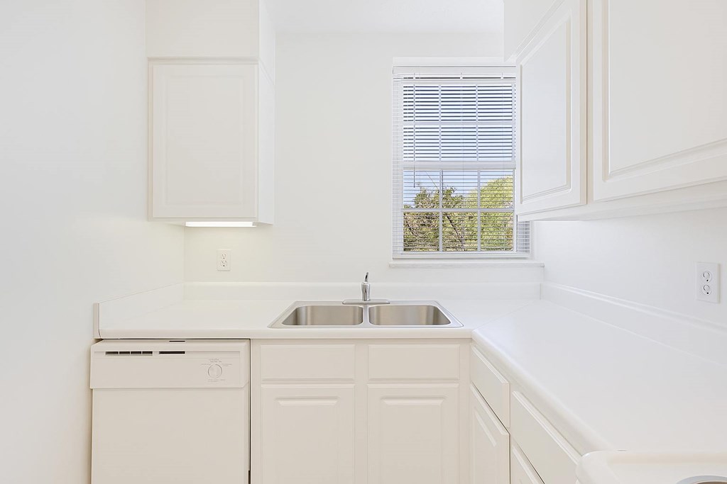 A white kitchen with a dishwasher and sink.