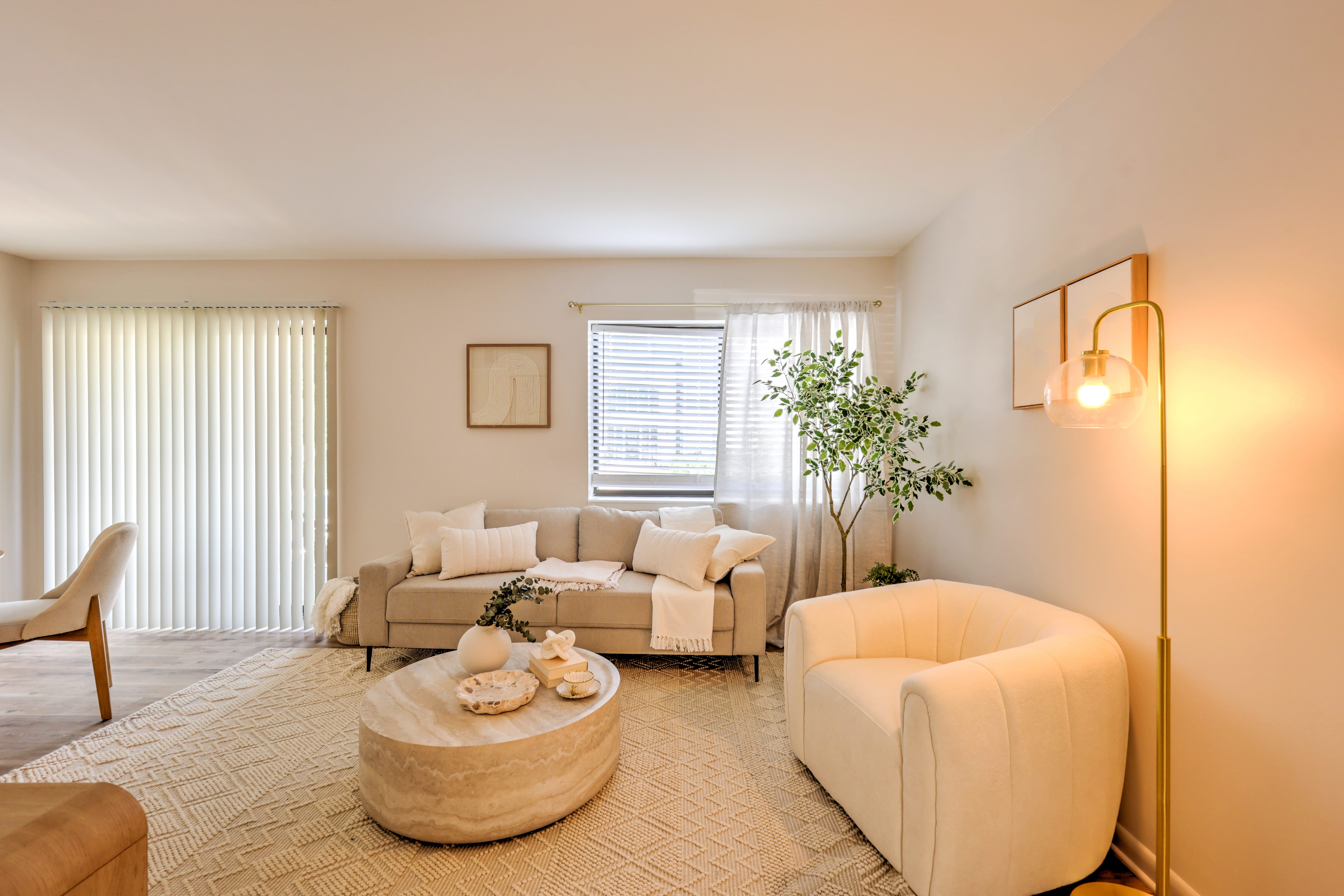 A living room with a white couch, a round coffee table, and a lamp on the wall.