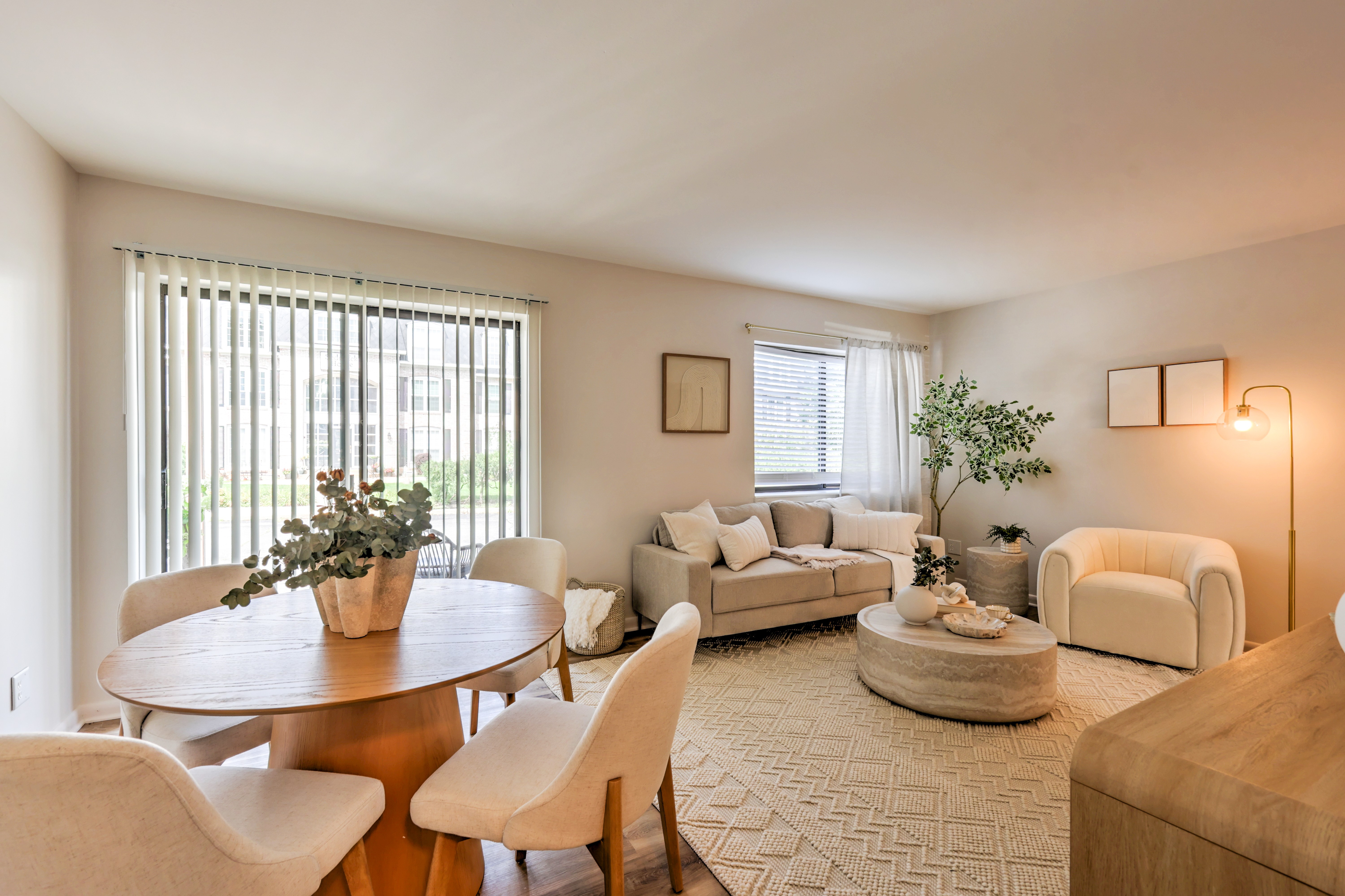 A living room with a round table and chairs, a couch, and a potted plant.