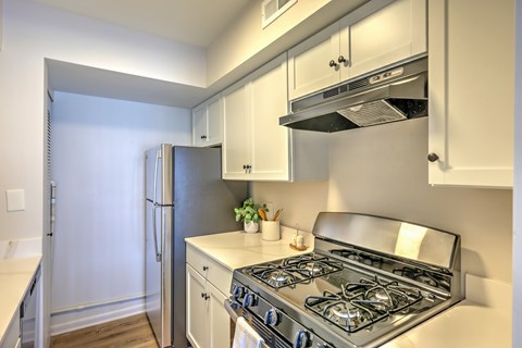 A modern kitchen with a stainless steel gas stove and white cabinets.