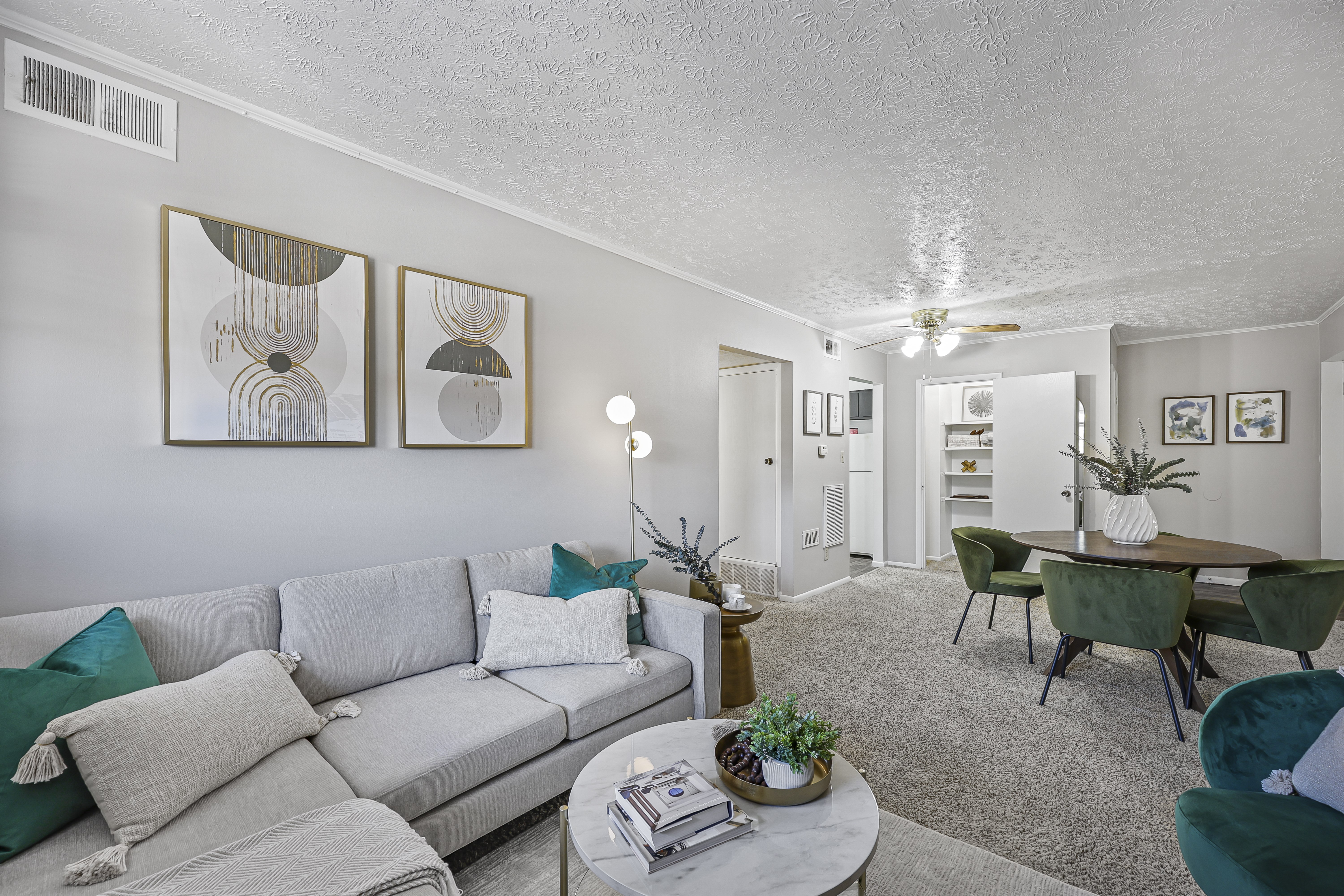 A living room with a grey couch and green chairs.