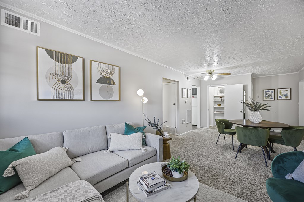 A living room with a grey couch and green chairs.
