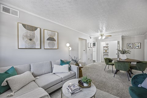 A living room with a grey couch and green chairs.