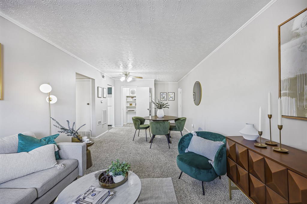 A living room with a grey couch, a green chair, a coffee table and a dining table.