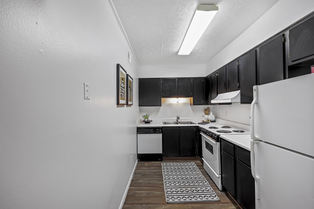 A kitchen with black cabinets and white appliances.