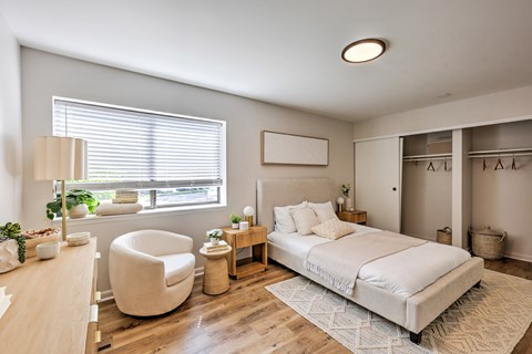 A bedroom with a large bed, a chair, and a desk.