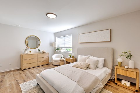 A bedroom with a large bed, a dresser, and a mirror.