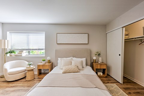 A bedroom with a large bed, a chair, and a painting on the wall.
