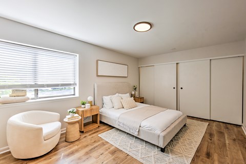 A bedroom with a large bed, a chair, and a nightstand.