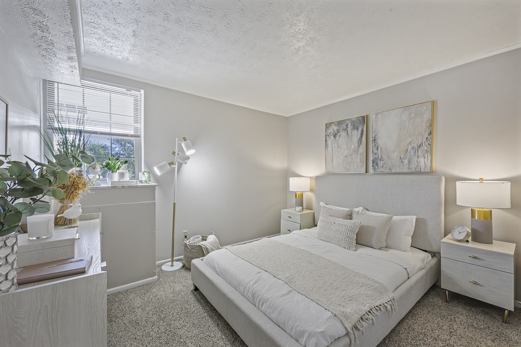 A bedroom with a large bed, two nightstands, and a window.