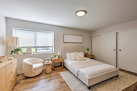 A bedroom with a large bed, a chair, and a nightstand.