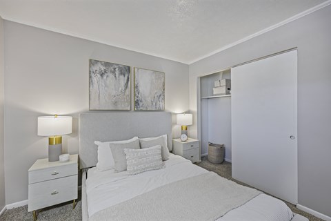 A white bedroom with a bed, nightstands, and two lamps.