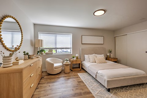 A well-lit bedroom with a large bed and a chair.