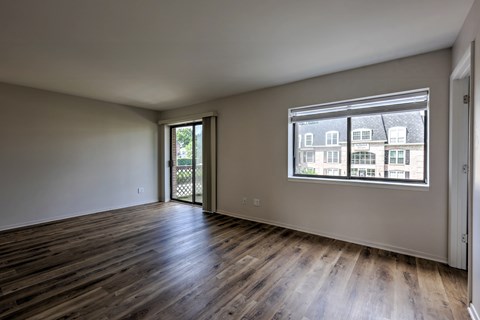 A room with wooden floors and a window showing a view of buildings outside.