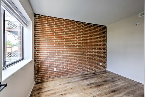 A room with a red brick wall and wooden flooring.