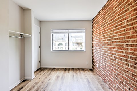 A room with a brick wall and a window.