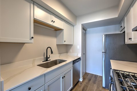 A modern kitchen with white cabinets and a black stove top.
