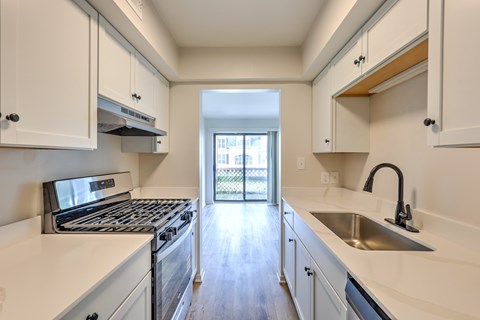 A kitchen with white cabinets and a stainless steel sink.