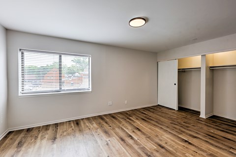 A room with wooden floors and a window with blinds.