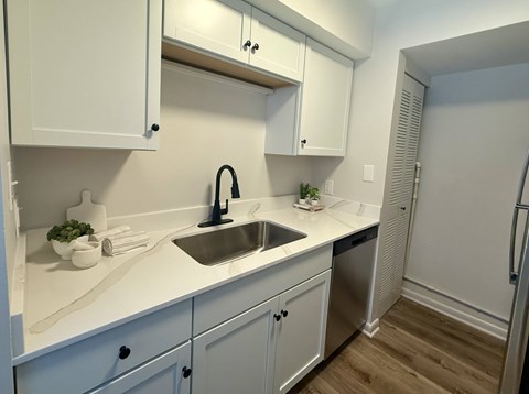 A kitchen with white cabinets and a stainless steel sink.
