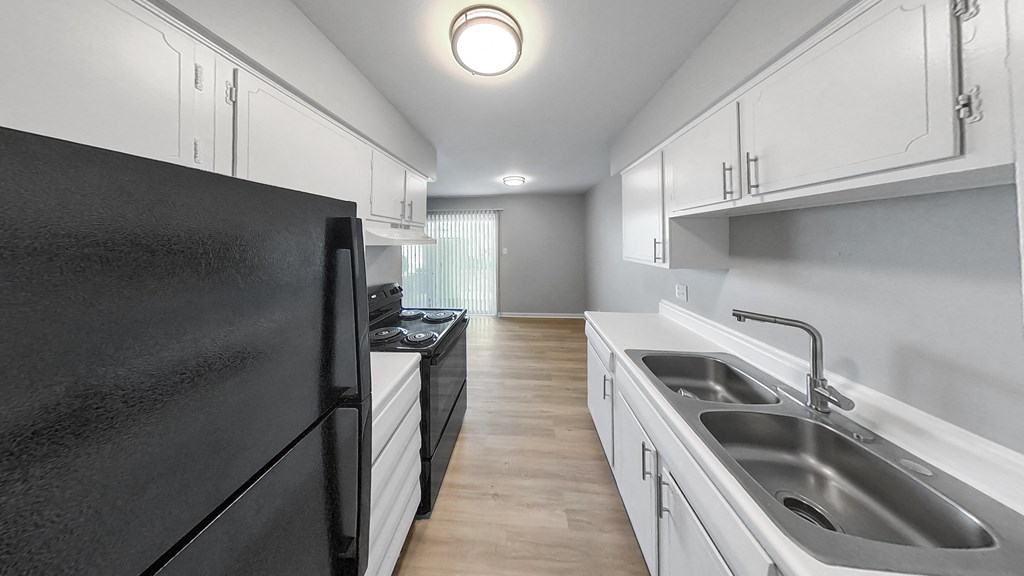 an empty kitchen with black appliances and white cabinets
