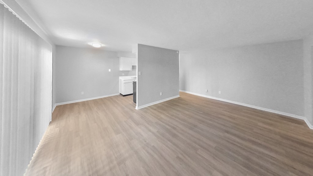 the living room and kitchen of an empty apartment with wood flooring