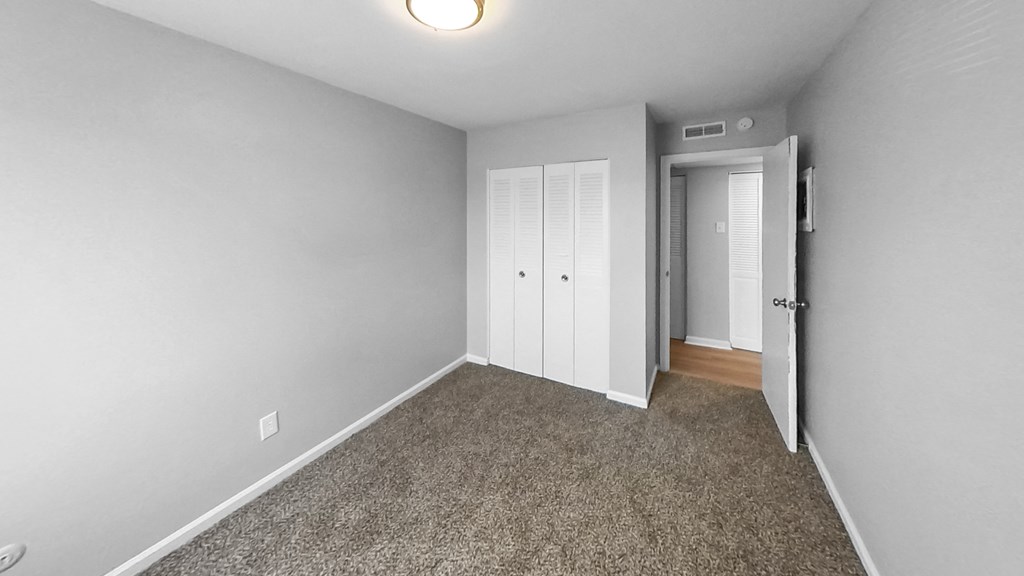 a bedroom with a carpeted floor and a door to a closet