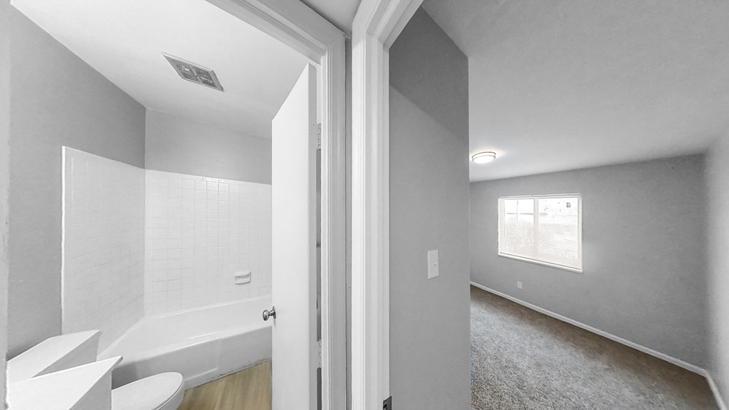 the living room and bathroom of a house with gray walls and a white bath tub
