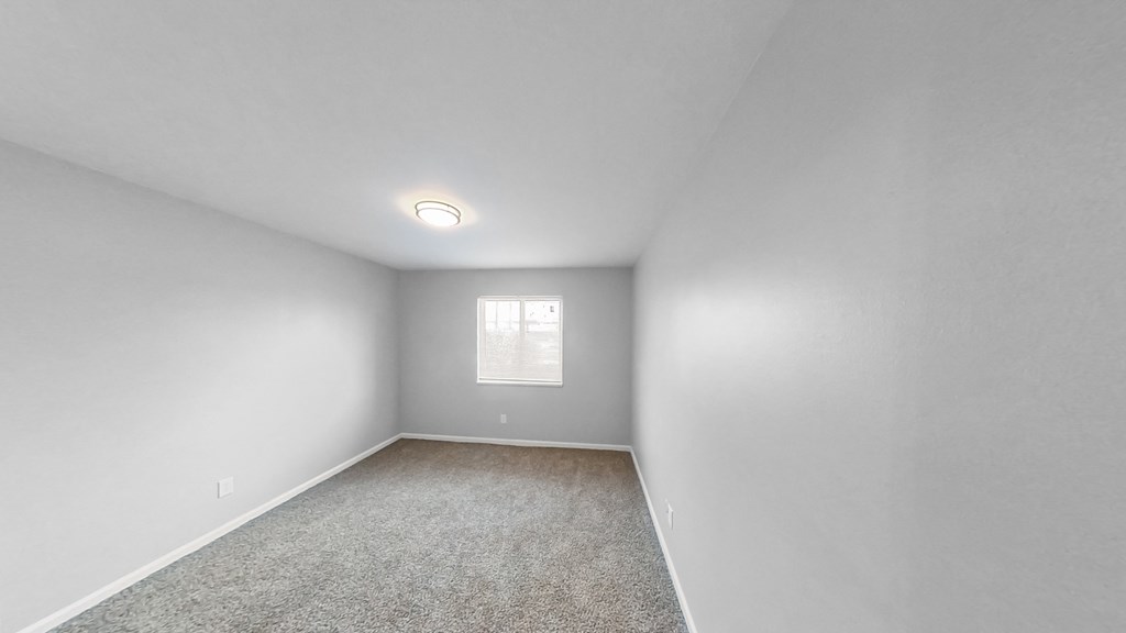 an empty room with white walls and a window