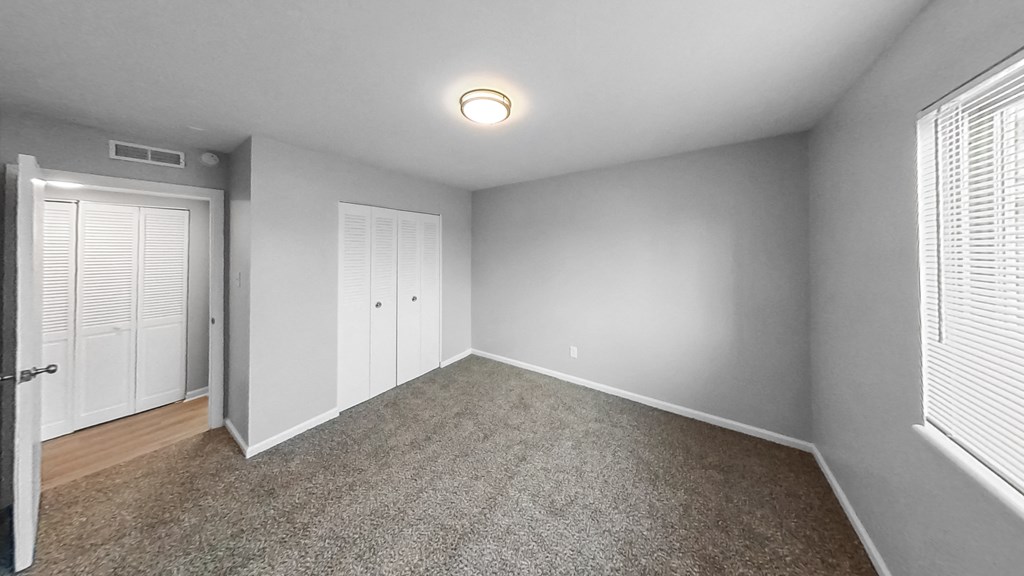 an empty room with a door to a closet and a window