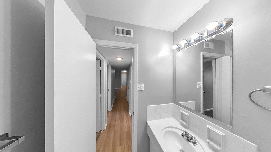 a bathroom with a sink and a mirror and a hallway