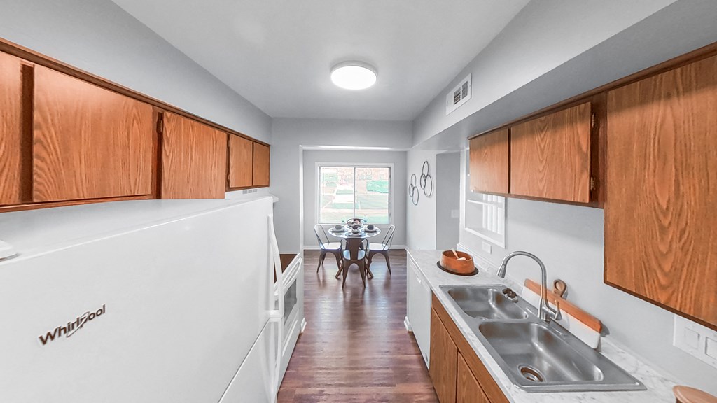 a kitchen with wooden cabinets and a sink and a dining room with a table