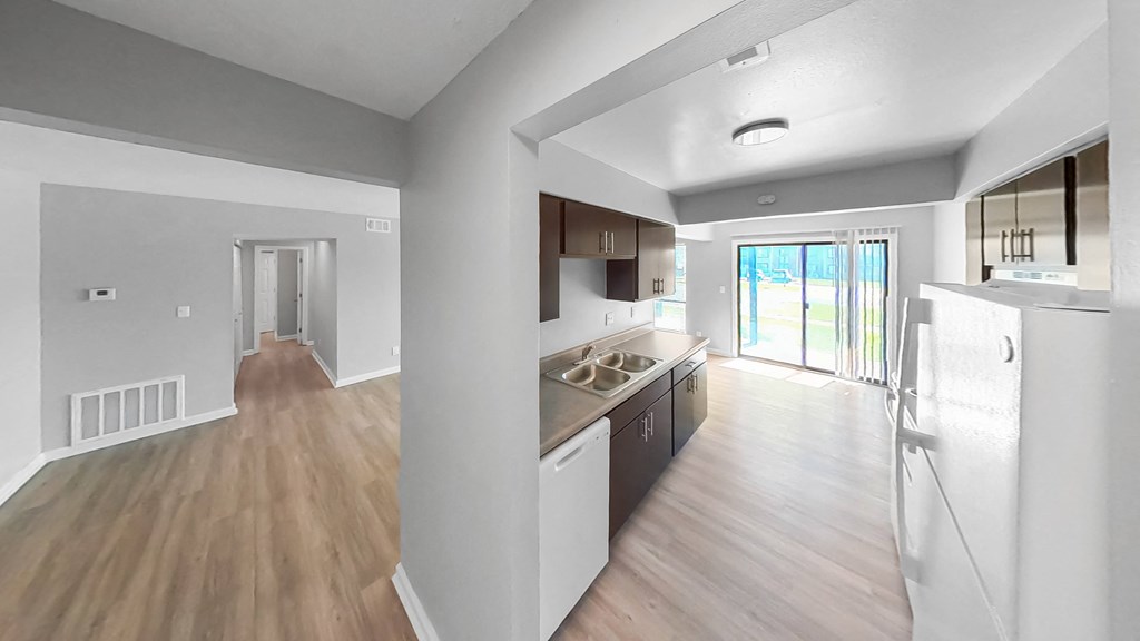an open kitchen and living room with wood flooring and a door to a balcony