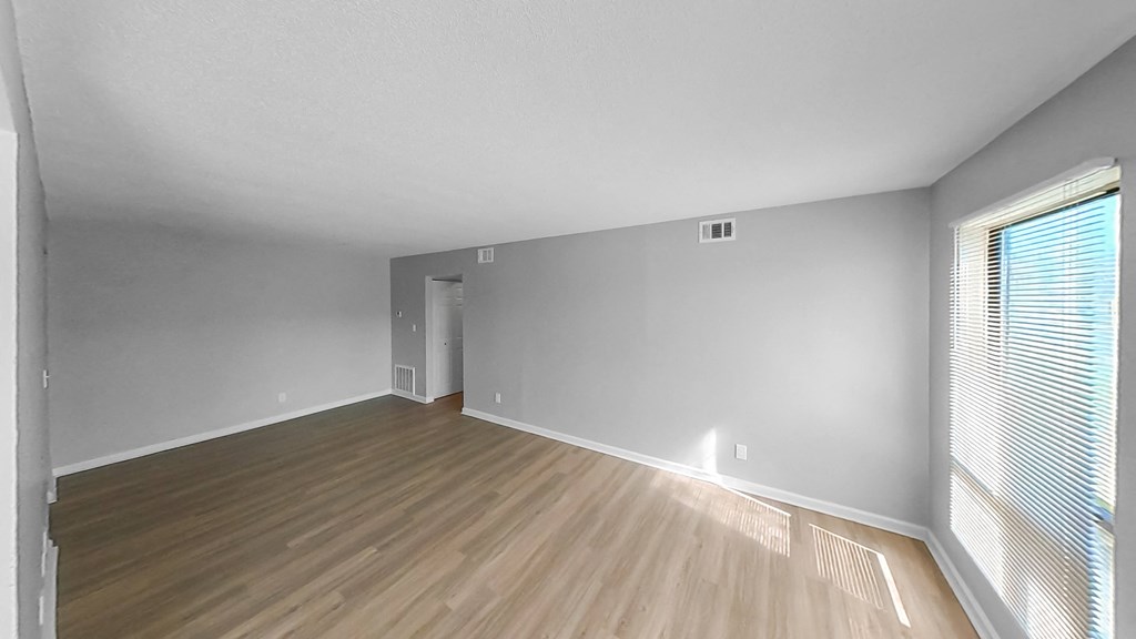 an empty living room with wood flooring and a large window