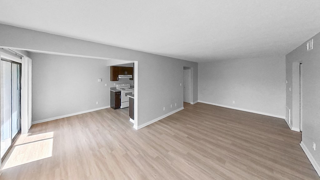 the living room and kitchen of an empty apartment with wood flooring
